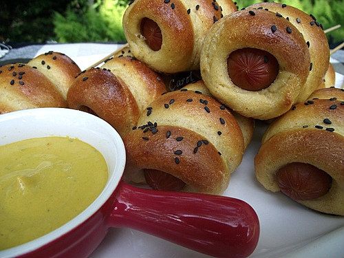 /><br/> <br/> BAKED MINI CORN DOGS<br/> (Source: adapted from Food Network Magazine June/July 2009)<br/> <br/> 1 c. milk<br/> 1 (1/4 oz.) pkg. active dry yeast (2 1/4 tsp.)<br/> 2 Tbsp. extra virgin olive oil<br/> 2 Tbsp. packed light brown sugar<br/> 1 c. fine yellow cornmeal<br/> 1 1/4 c. bread flour, plus more for dusting and kneading<br/> 1 tsp. salt<br/> 1/4 tsp. baking soda<br/> 1/4 tsp. cayenne pepper<br/> 8 hot dogs, halved crosswise<br/> 1 large egg, beaten<br/> 1 Tbsp. black sesame seeds. optional<br/> <br/> Warm the milk to about 110 degrees in a saucepan or in the microwave; pour into a medium bowl. Sprinkle the yeast over the warmed milk; whisk to blend. Let mixture sit for about 2 minutes to allow yeast to dissolve.<br/> <br/> Stir in the olive oil, brown sugar and cornmeal with a wooden spoon. Add all but 1/4 cup of the flour, salt, baking soda and cayenne; stir to make a sticky dough.<br/> <br/> Turn the dough out onto a lightly floured surface; knead, using the reserved 1/4 cup flour, adding more if needed, until smooth but still slightly tacky, about 5 minutes.<br/> <br/> Shape dough into a ball, place in a lightly oiled bow, turning to coat top of dough. Cover bowl with plastic wrap and let rise in a warm place until doubled in size, about 45-60 minutes.<br/> <br/> Preheat the oven to 425 degrees. Line a baking sheet with parchment paper.<br/> <br/> Turn the dough out onto a lightly floured surface; divide into 18 pieces. With your palms, roll each piece of dough into a 10